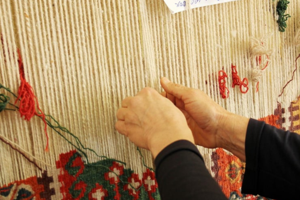 An artisan weaving a Kashmiri carpet by hand, preserving Kashmiri culture